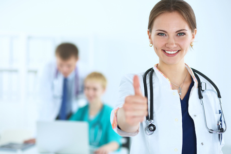 A female doctor shows a sign okay standing in hospitalの写真素材