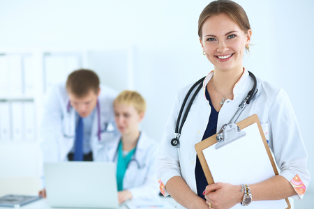 Attractive female doctor with folder in front of medical group .の写真素材