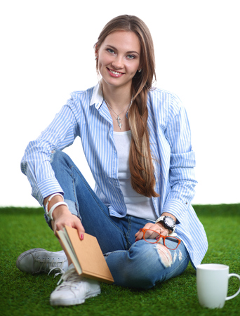 Young woman sitting with book on grass .の写真素材