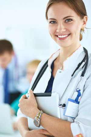 Attractive female doctor with folder in front of medical group .の写真素材