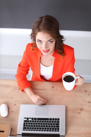 Attractive woman sitting at desk in office, working with laptopの写真素材