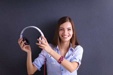Smiling girl with headphones sitting on the floor near wall.の写真素材