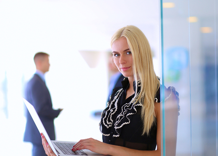 Young businesswoman holding a laptop, standing on office .の写真素材