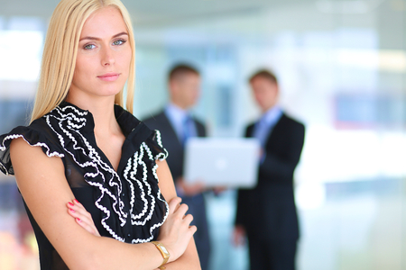 Business woman standing in foreground with a tablet in her handsの写真素材