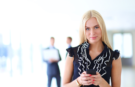 Beautiful businesswoman using cell phone , standing in office .の写真素材