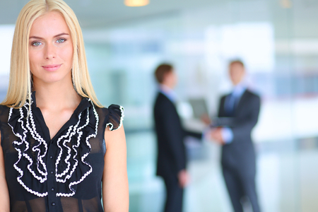 Business woman standing in foreground with a tablet in her handsの写真素材