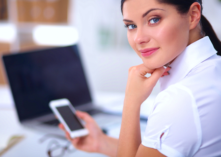 Businesswoman sending message with smartphone in officeの写真素材