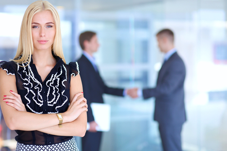 Business woman standing in foreground in office .の写真素材