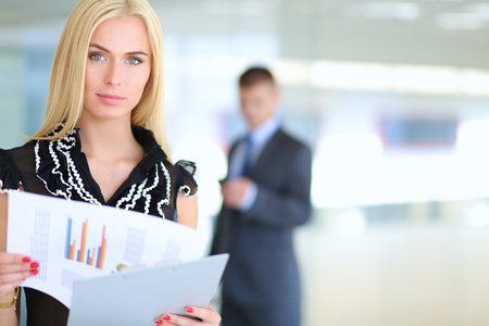 Business woman standing in foreground with a folder in her hands .の写真素材