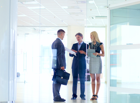 Business woman standing with her staff in background at modern office .の写真素材