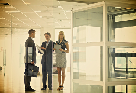 Business woman standing with her staff in background at modern office .の写真素材