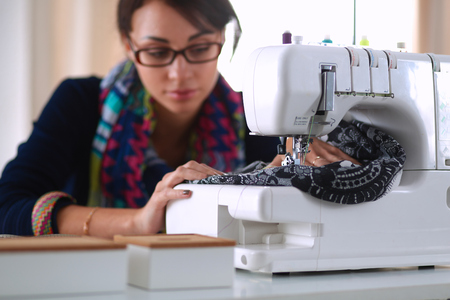Young woman sewing while sitting at her working place .の写真素材