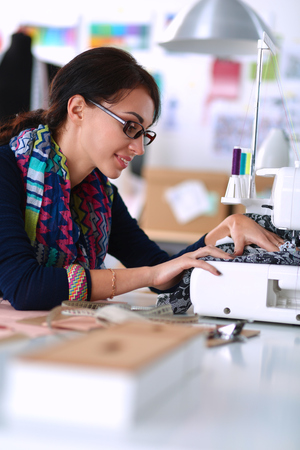 Young woman sewing while sitting at her working place .の写真素材