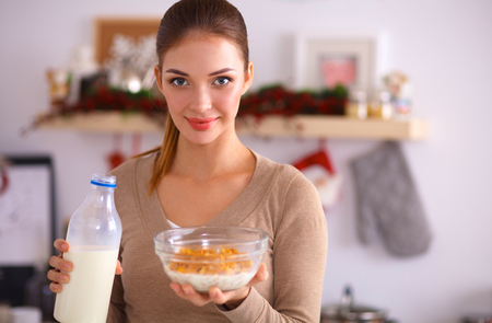 A young woman eating cereals in her kitchenの写真素材