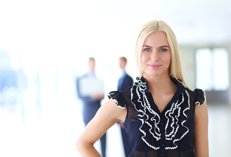 Business woman standing in foreground in office .の写真素材