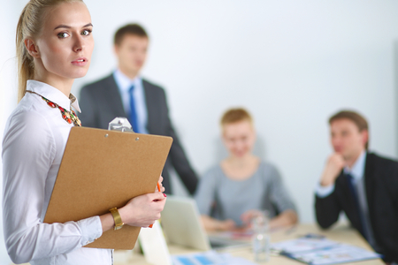 Portrait of a young woman working at office standing with folder .の写真素材