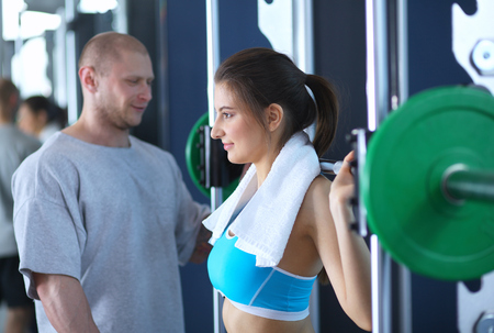 Beautiful woman at the gym exercising with her trainer .の写真素材