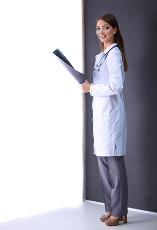 Portrait a female doctor with X-ray picture standing near grey wallの写真素材