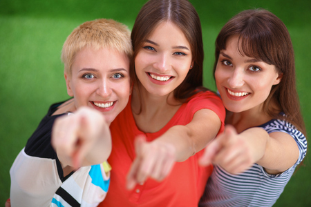 Portrait of three young women, standing together and pointing you.の写真素材