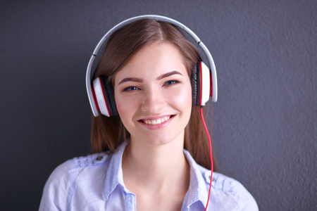 Smiling girl with headphones sitting on the floor near wallの写真素材