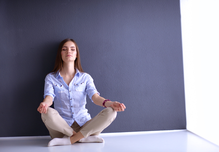 Young woman sitting on the floor near dark wall.の写真素材