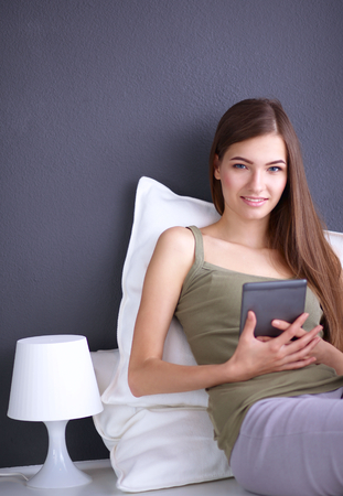 Portrait of a pretty brunette woman sitting on the floor with a pillow and plane tableの写真素材