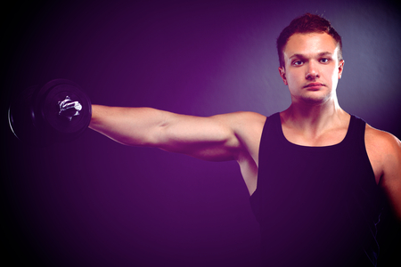 Handsome muscular man working out with dumbbells.の写真素材