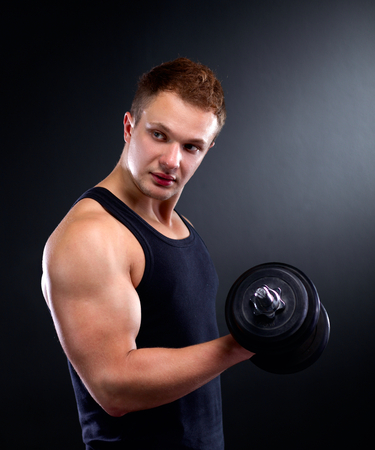 Handsome muscular man working out with dumbbells.の写真素材