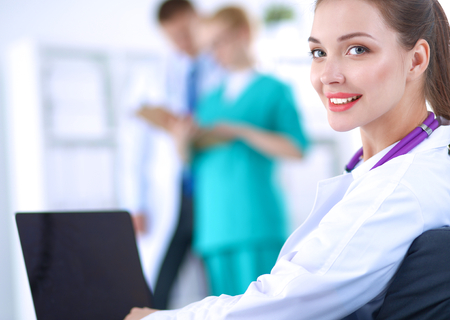 Beautiful young smiling female doctor sitting at the desk.の写真素材