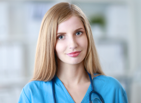 Happy doctor woman is standing in the near windowの写真素材