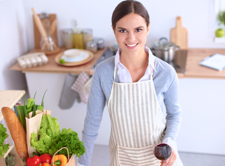 Woman with shopping bags in the kitchen at homeの写真素材