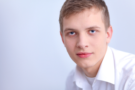 Portrait of young man  sitting on gray backgroundの写真素材