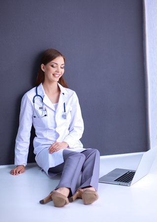 A female doctor working sitting on gray  backgroundの写真素材