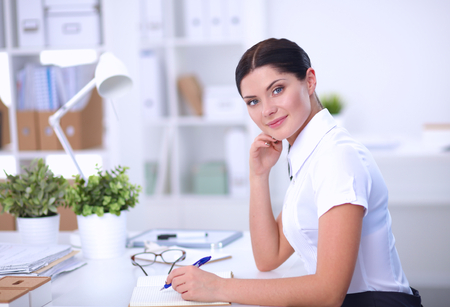 Attractive businesswoman sitting in the office, isolatedの写真素材