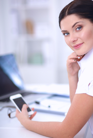 Businesswoman sending message with smartphone in officeの写真素材