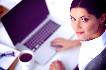 Portrait of a businesswoman sitting at a desk with a laptop, isolatedの写真素材
