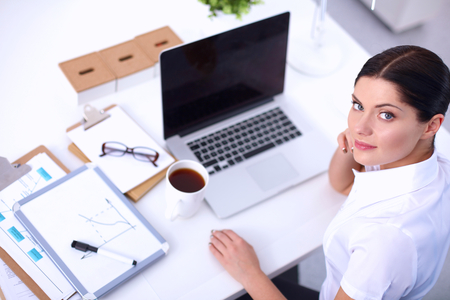 Portrait of a businesswoman sitting at a desk with a laptop, isolatedの写真素材