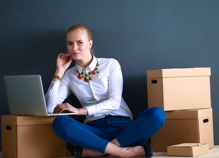 Woman sitting on the floor near a boxes  with laptop .の写真素材