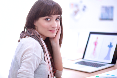 Portrait of attractive female fashion designer sitting at office desk.の写真素材