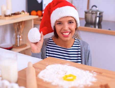 Christmas baking santa woman smiling happy having fun with Christmas preparations wearing Santa hatの写真素材