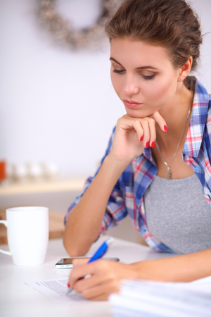 Beautiful young woman writing something in her note pad , isolatedの写真素材