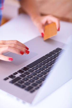 Woman online shopping using computer and credit card in kitchenの写真素材