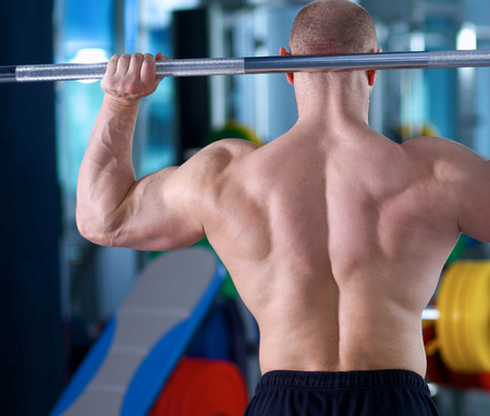 Bodybuilder standing with barbell in gym .の写真素材