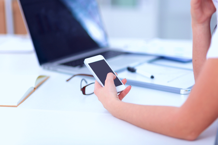Businesswoman sending message with smartphone in officeの写真素材