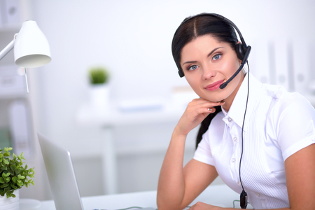 Portrait of beautiful business woman working at her desk with headset and laptopの写真素材