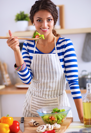 woman eating fresh salad in modern kitchen,の写真素材