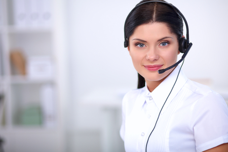 Portrait of beautiful business woman working at her desk with headset and laptopの写真素材