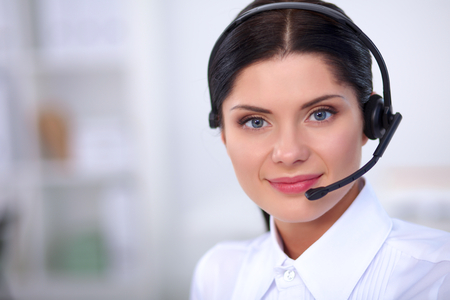 Portrait of beautiful business woman working at her desk with headset and laptopの写真素材