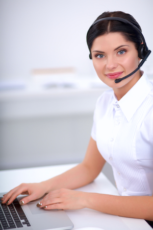 Portrait of beautiful business woman working at her desk with headset and laptopの写真素材