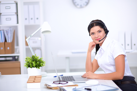 Portrait of beautiful business woman working at her desk with headset and laptopの写真素材